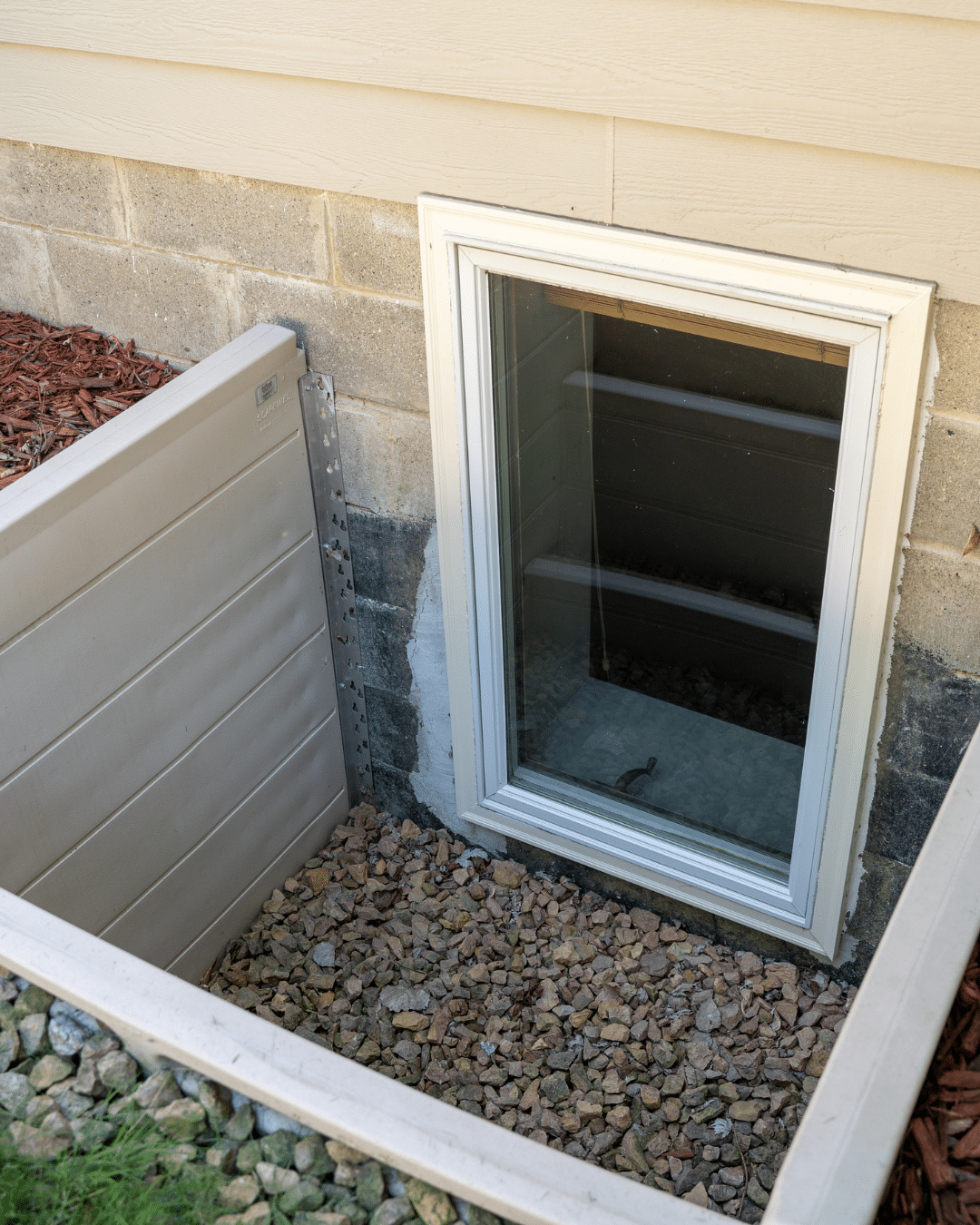 Technician inspecting and maintaining a window well to prevent frozen drainage and basement flooding in Fort Collins, CO